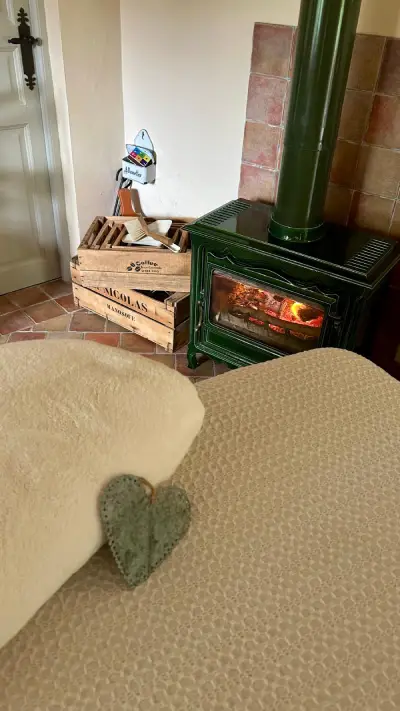 Poêle à bois allumé et plaid crème dans l’espace de soin du Clos du Soin